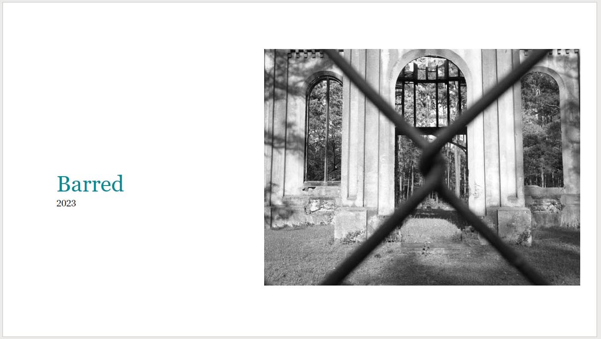 b&w photo of church ruins through a chain link fence